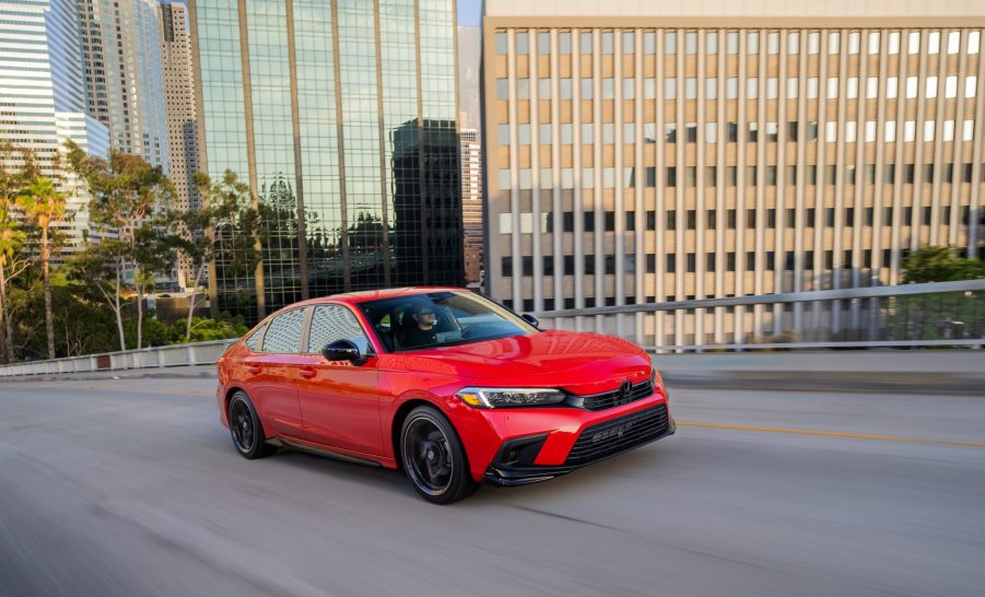 A red 2022 Honda Civic Sedan Sport with HPD Package drives through a city