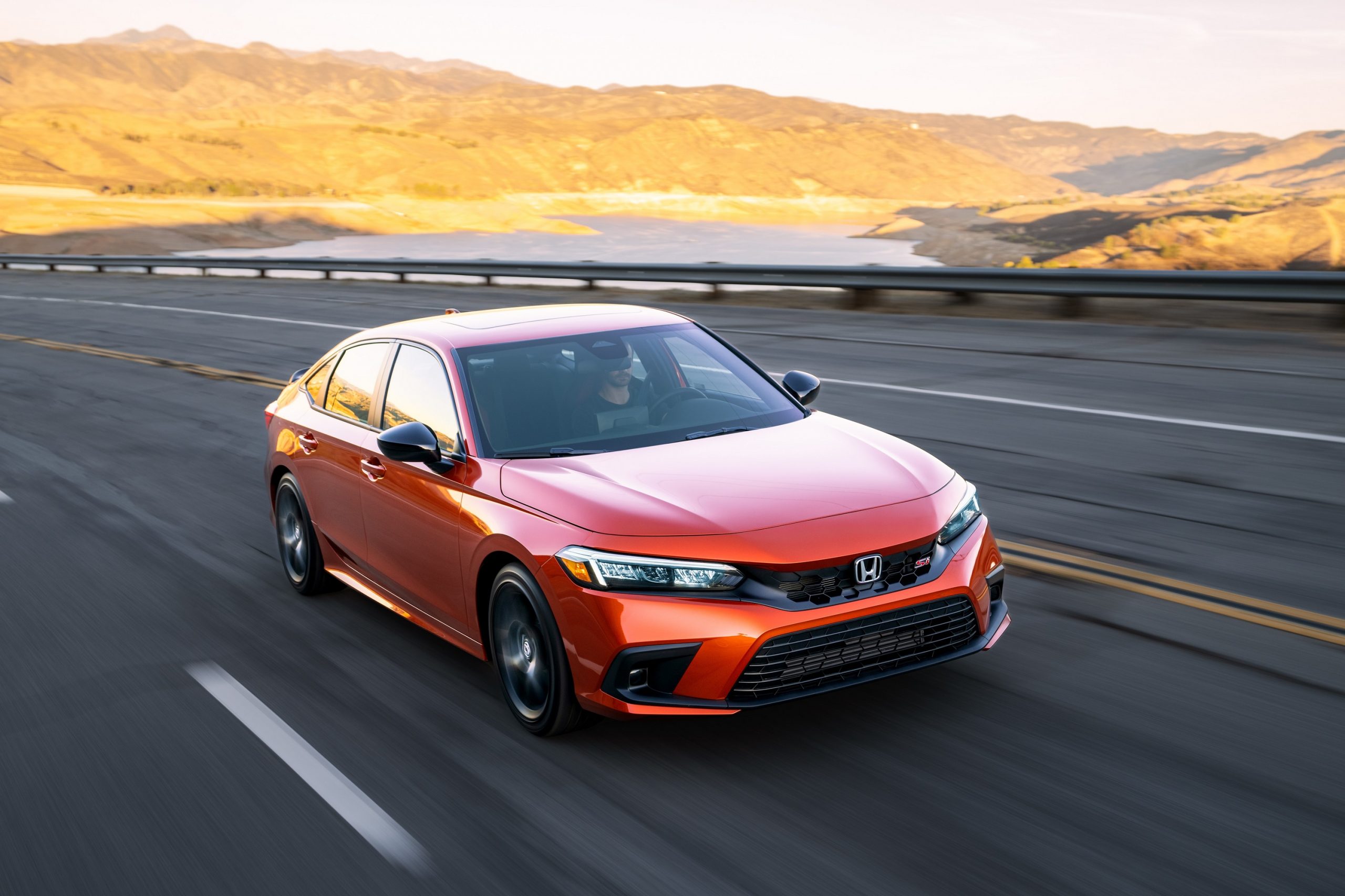 An orange 2022 Honda Civic Si shot from the front 3/4 on the highway