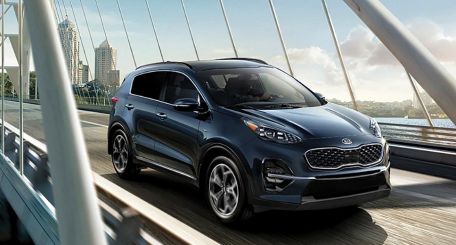 A blue 2022 Kia Sportage is driving on a bridge.