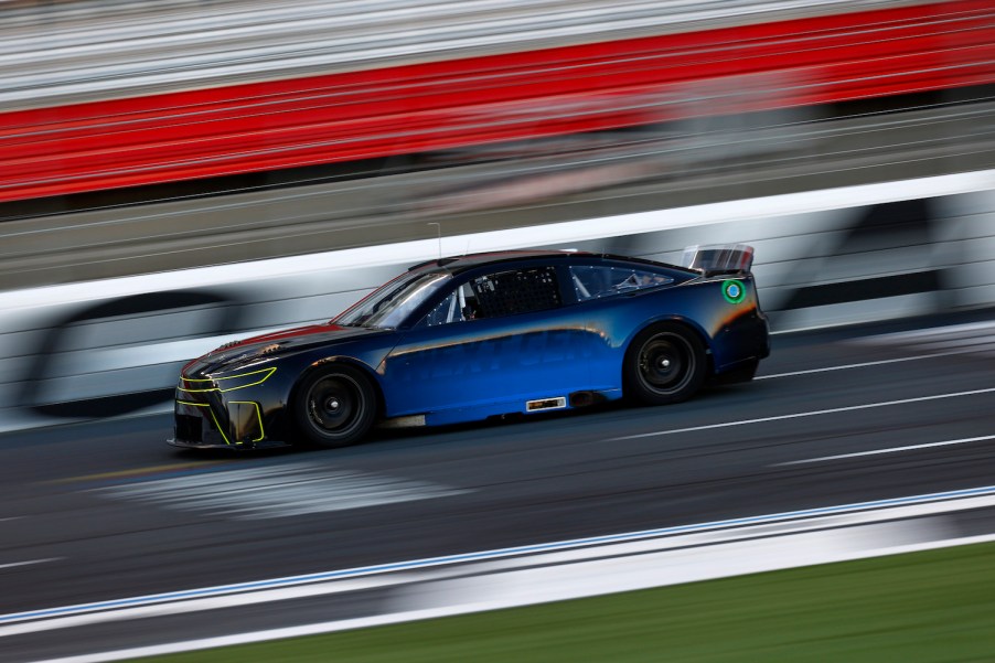 A blue NASCAR race car speeding down a racetrack, the background a blur.