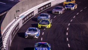 Seven NASCAR cup cars packed together and racing to win.