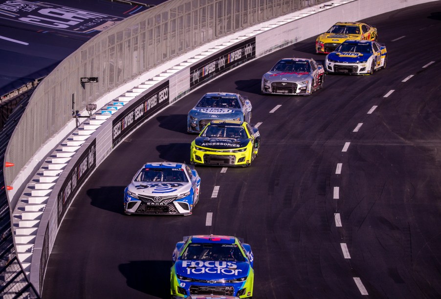 Seven NASCAR cup cars packed together and racing to win.