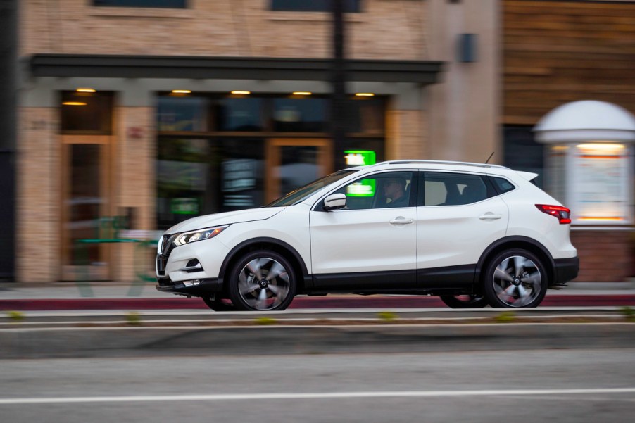 2022 Nissan Rogue Sport travels on a city street past storefronts