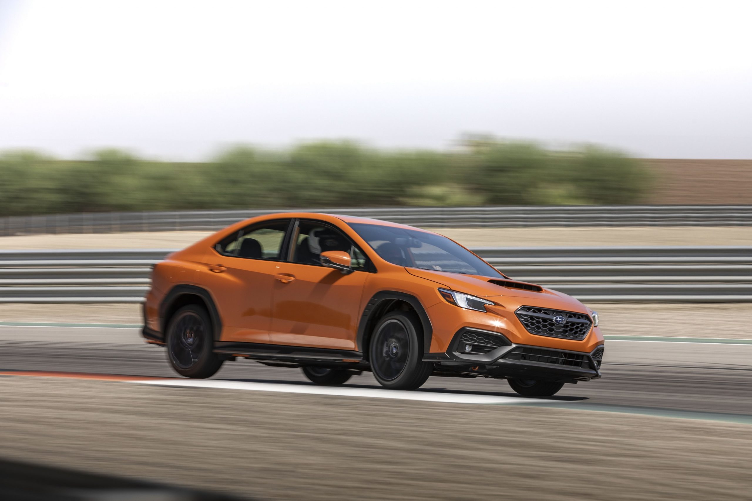 An orange 2022 Subaru WRX sports car shot in profile on track