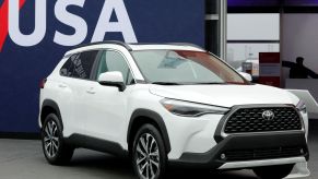 A white 2022 Toyota Corolla Cross in front of a blue and red background with USA written on it in white.