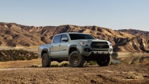 Promo shot of a gray Toyota Tacoma parked in front of a lake and mountains.