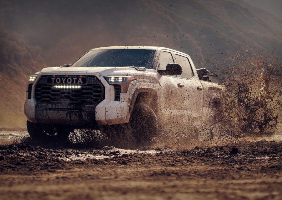 Toyota Tundra showing off its reliability by off-roading through deep mud, a steep gorge in the background.