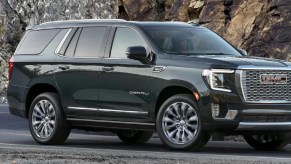 A black 2022 GMC Yukon driving past a mountain.