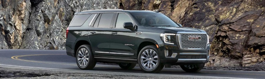 A black 2022 GMC Yukon driving past a mountain.