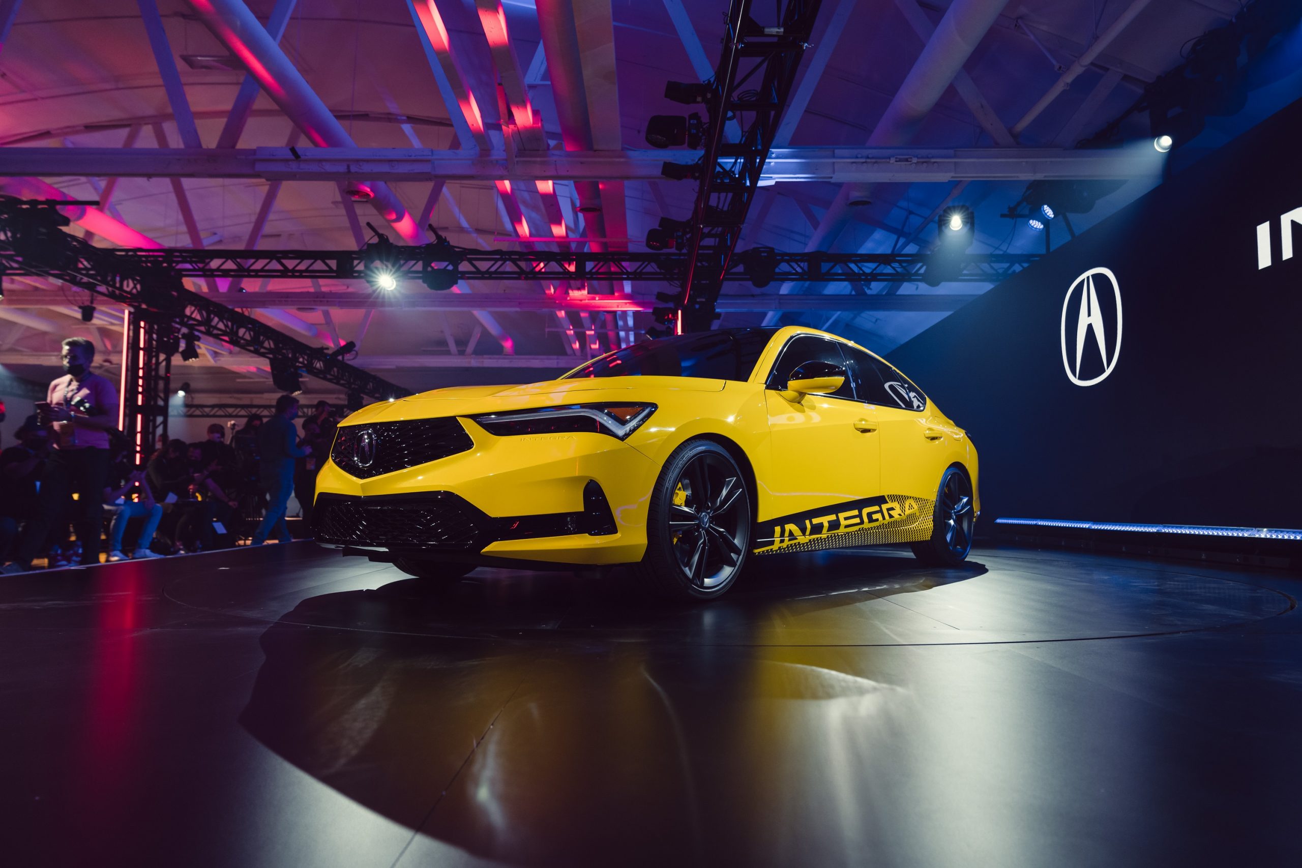 A yellow 2023 Acura Integra shot from the front 3/4 at its debut