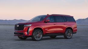 A 3/4 profile view of a red pre-production 2023 Cadillac Escalade V-Series SUV parked with mountains in the background.