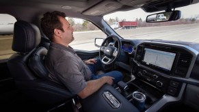 A man demonstrating Ford's BlueCruise software by driving his F 150 pickup truck hands-free.