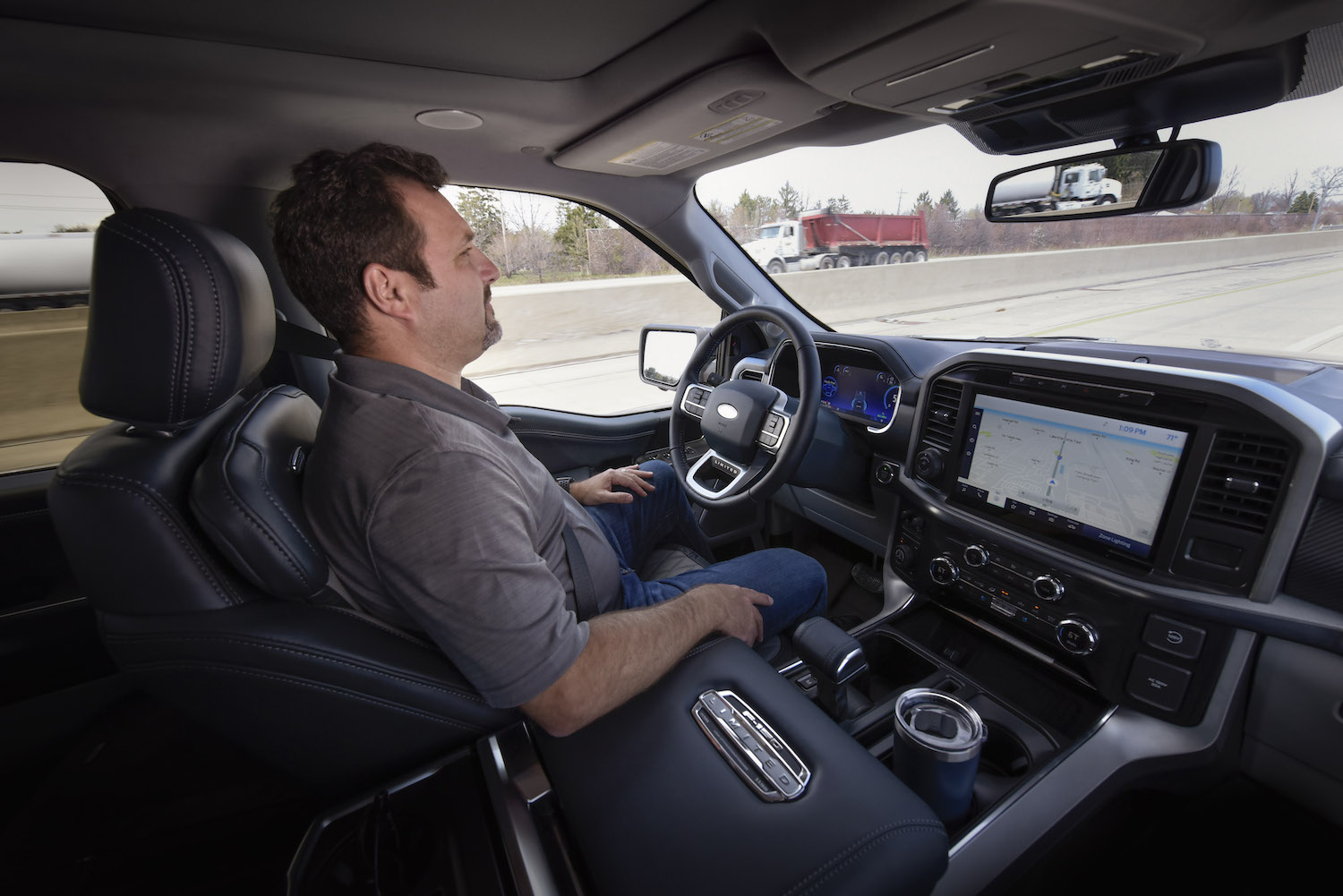 A man demonstrating Ford's BlueCruise software by driving his F 150 pickup truck hands-free.