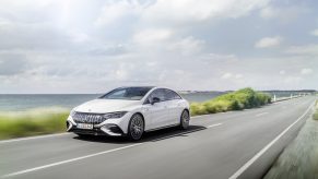 A white 2023 Mercedes-AMG EQE drives down a road