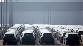 A large number of dark-colored Porsche Cayenne SUVs gathered in a parking lot for emissions-related recall work