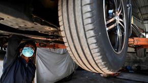 A mechanic under a car potentially changing fluids like transmission fluid.