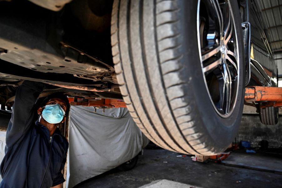 A mechanic under a car potentially changing fluids like transmission fluid.