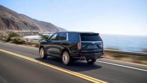 The Cadillac Escalade cruises near a coast.