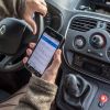 A man being a distracted driver by watching his phone rather than the road, which is a bad driving habit.