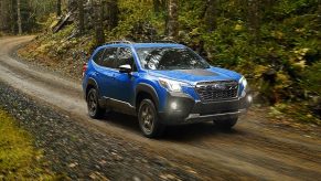 Geyser Blue 2022 Subaru Forester driving through a forest