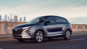 A 2022 Dusk Blue Hyundai Nexo compact SUV is driving on the road.