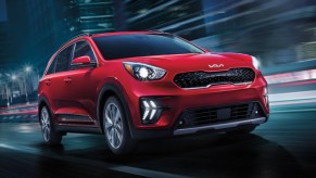 A red Kia Niro Plug-in Hybrid SUV is driving.