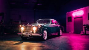 A blue-and-silver Lunaz classic Bentley Continental Flying Spur electric conversion by a garage