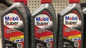 Three bottles of motor oil, such as synthetic, natural, or a mix, sitting on a shelf.