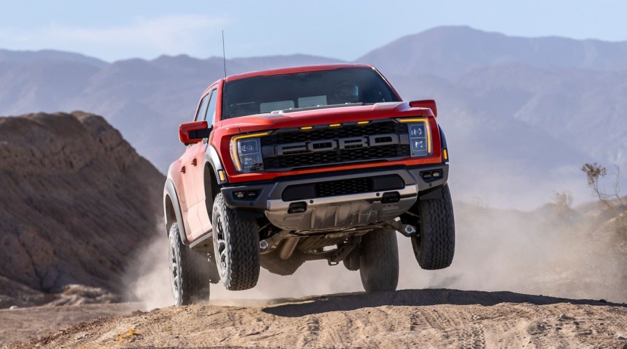 Orange 2022 Ford F-150 Raptor jumping on sandy terrain, highlighting possible release of F-150 Lightning Raptor