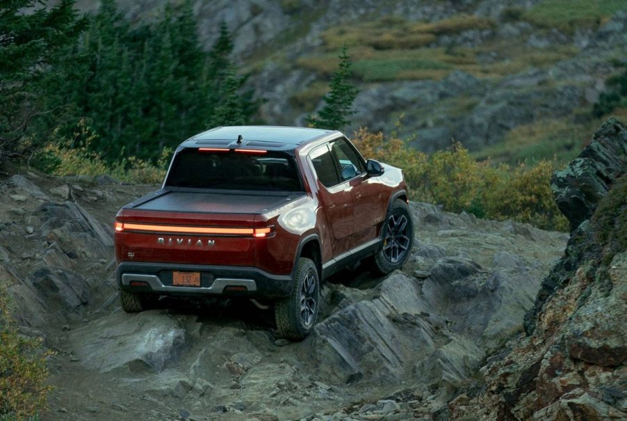 Orange-red 2022 Rivian R1T driving off-road, highlighting advantages of electric vehicles vs. gas-powered cars