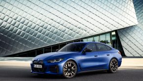 A 3/4 front view of a blue 2022 BMW i4 M50 sedan in front of a silver building.