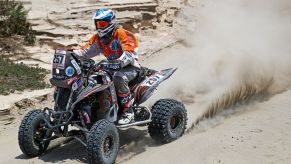 A person riding on an ATV in a dessert area.