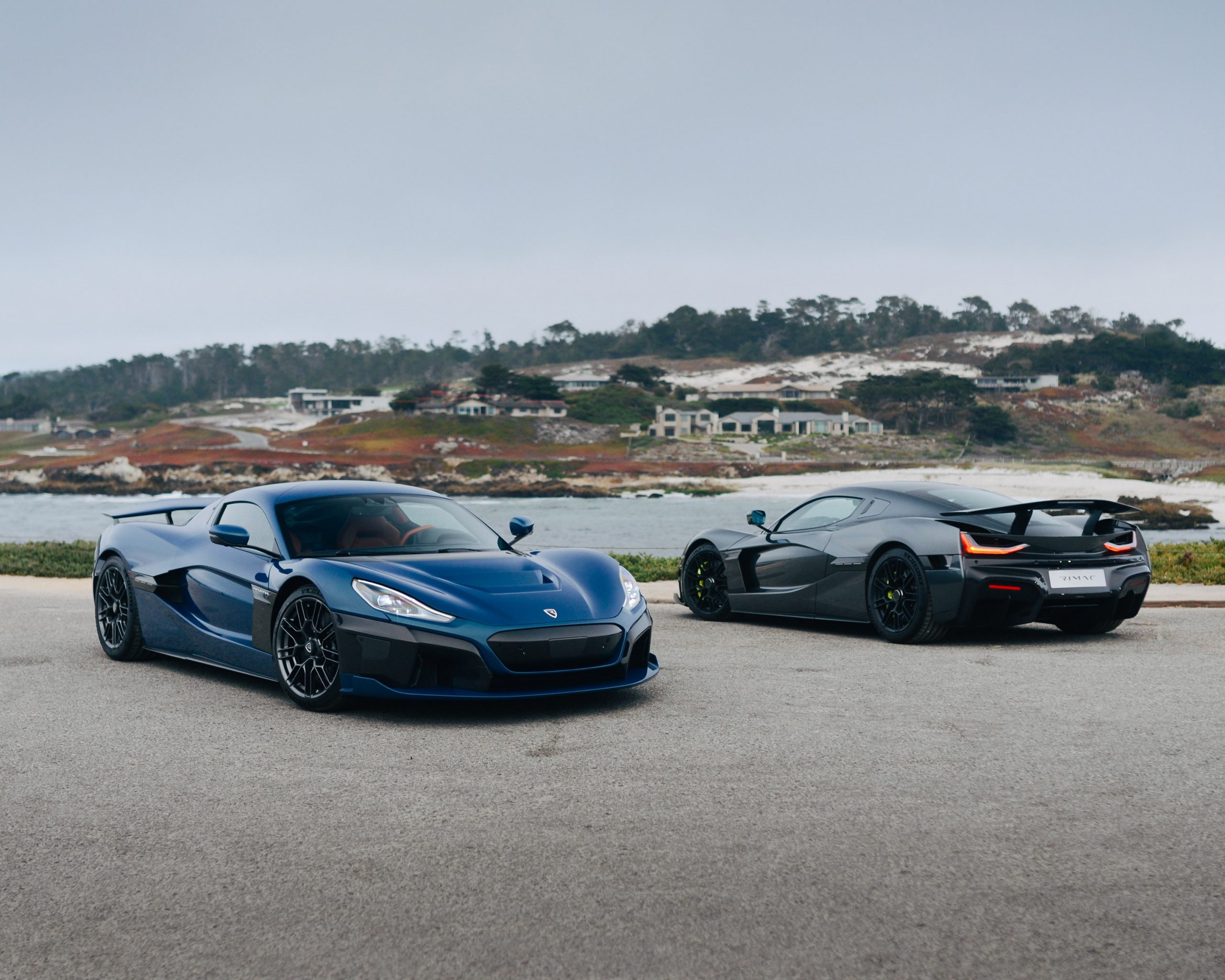 A pair of Rimac Nevera electric cars shot by the sea on a cloudy day