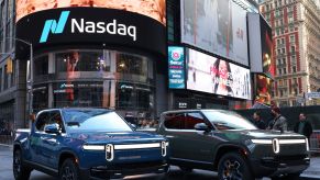 Two Rivian trucks, aided by Ford's Rivian investment, parked in a large city.