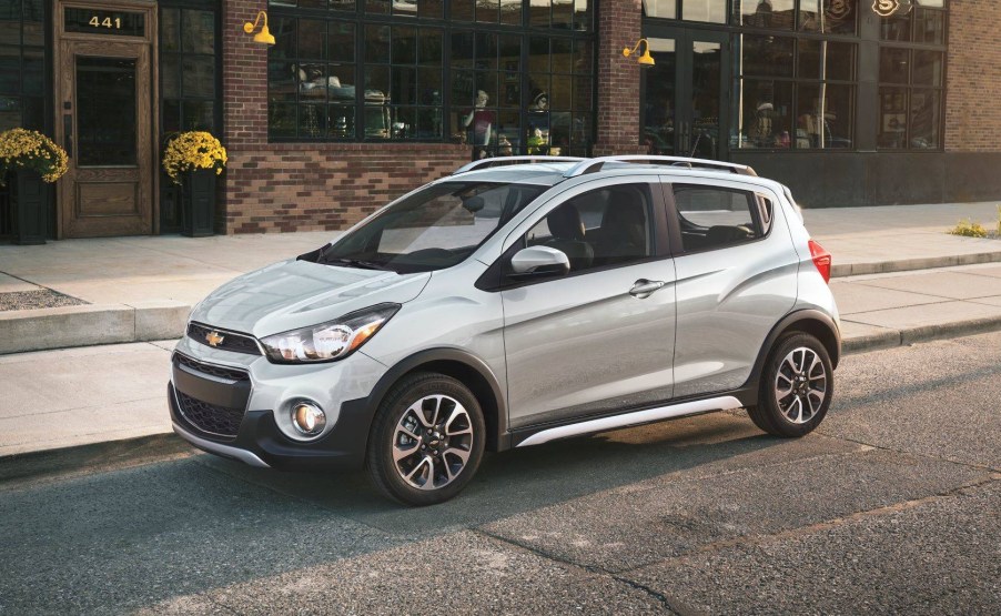 Silver 2022 Chevrolet Spark, the cheapest car available to buy in 2022, parked next to a sidewalk