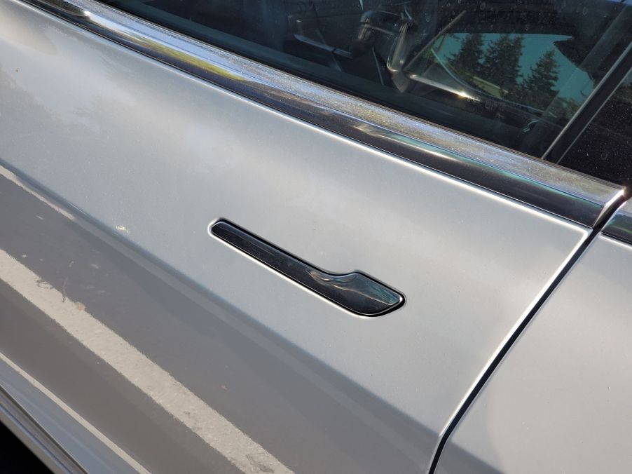 A black Tesla door handle on a silver Tesla.