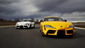 Two Toyota Supras on in white and one in yellow