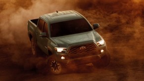 A green Toyota Tacoma is driving off-road.