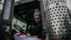 A potentially seasoned truck driver sitting in his truck.