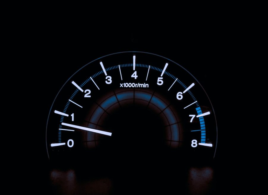 The backlit tachometer of a car that is idling its engine while parked.