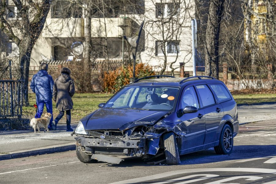 A broken blue car on the side of the road