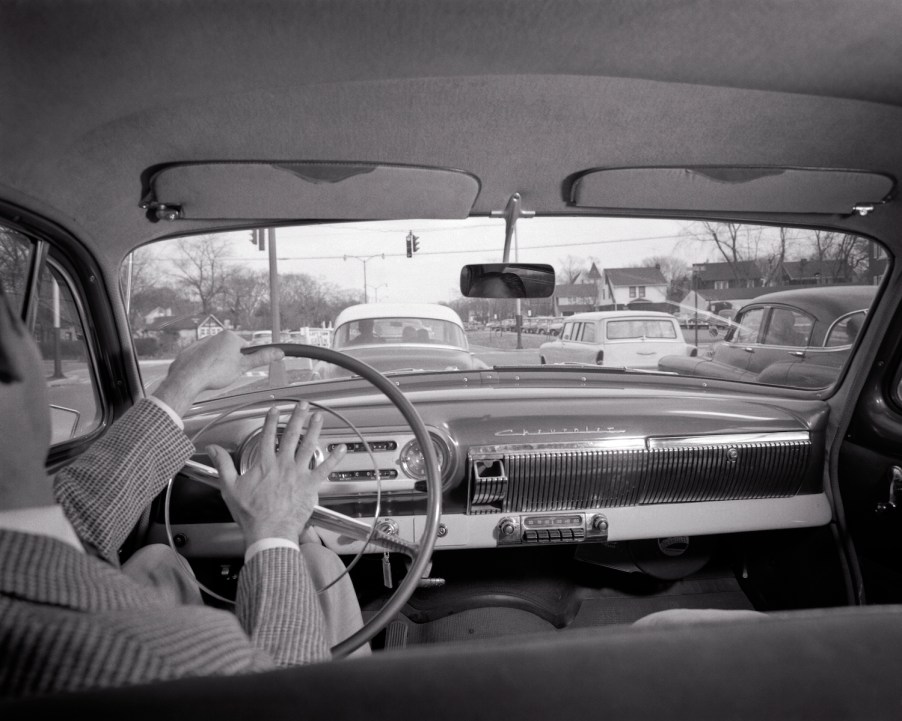 The driver of a vintage Chevrolet honking his horn at slow traffic.