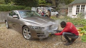 Man steam cleaning a luxury car on a home visiting valet service, England UK