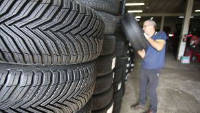 Rows of tires off the cars, not checking tire pressure, with a man pulling a tire off.