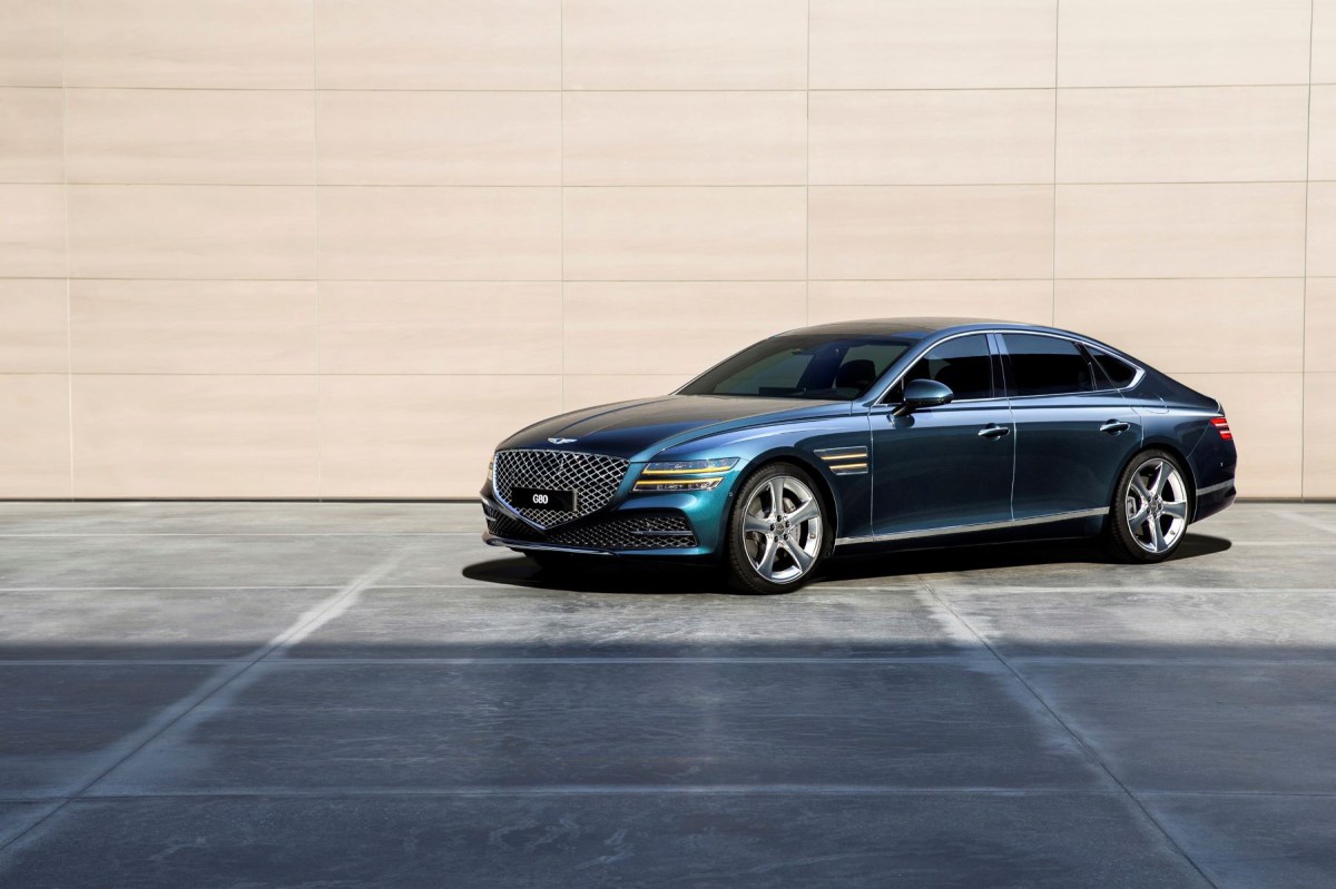 A side shot of a 2022 Genesis G80 parked in front of a cream colored wall