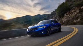 Blue production spec 2023 Acura Integra driving on mountain roads, front end