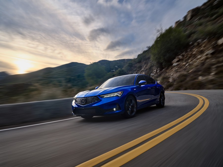 Blue production spec 2023 Acura Integra driving on mountain roads, front end