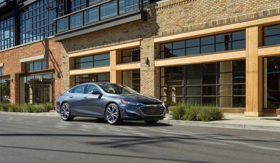 The 2021 Chevrolet Malibu midsized sedan parked outside a wood and brick building