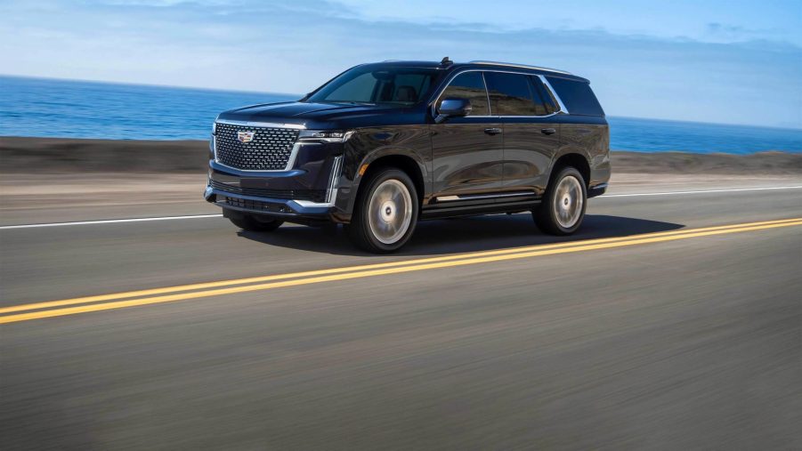 A dark colored 2022 Cadillac Escalade driving down a road.