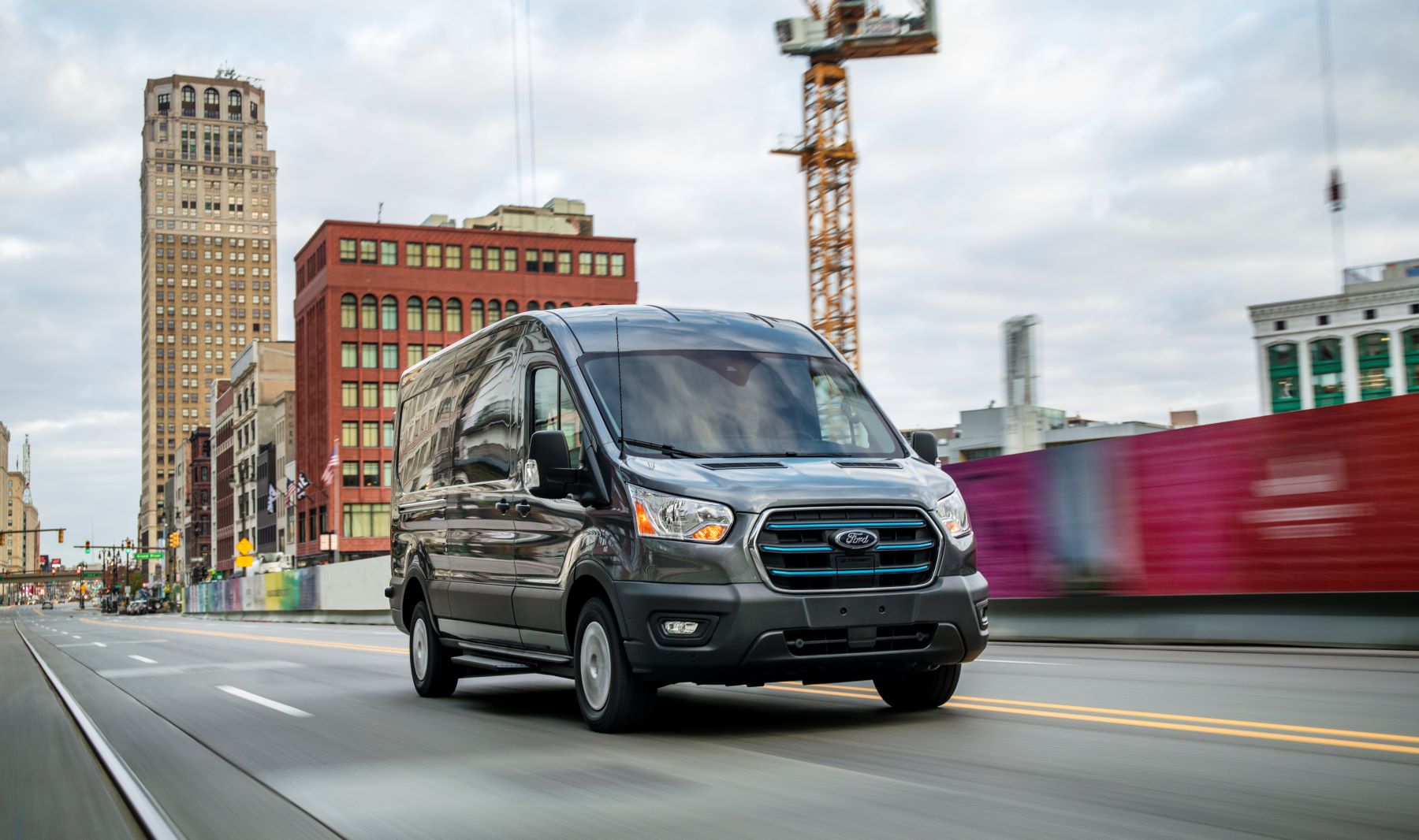 2022 Ford E-Transit all-electric commercial cargo van driving past a construction site